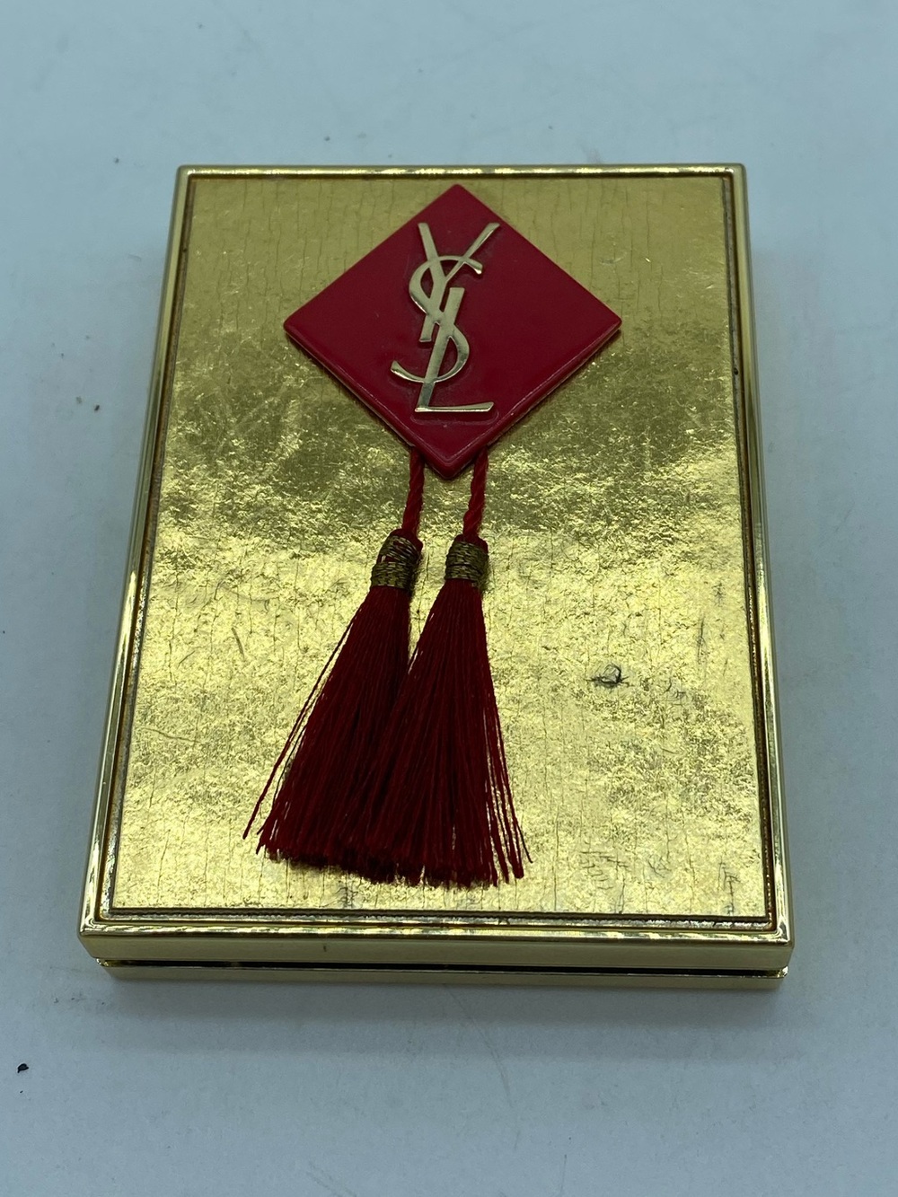 Yves Saint Laurent Gold Compact with Red Tassel Emblem